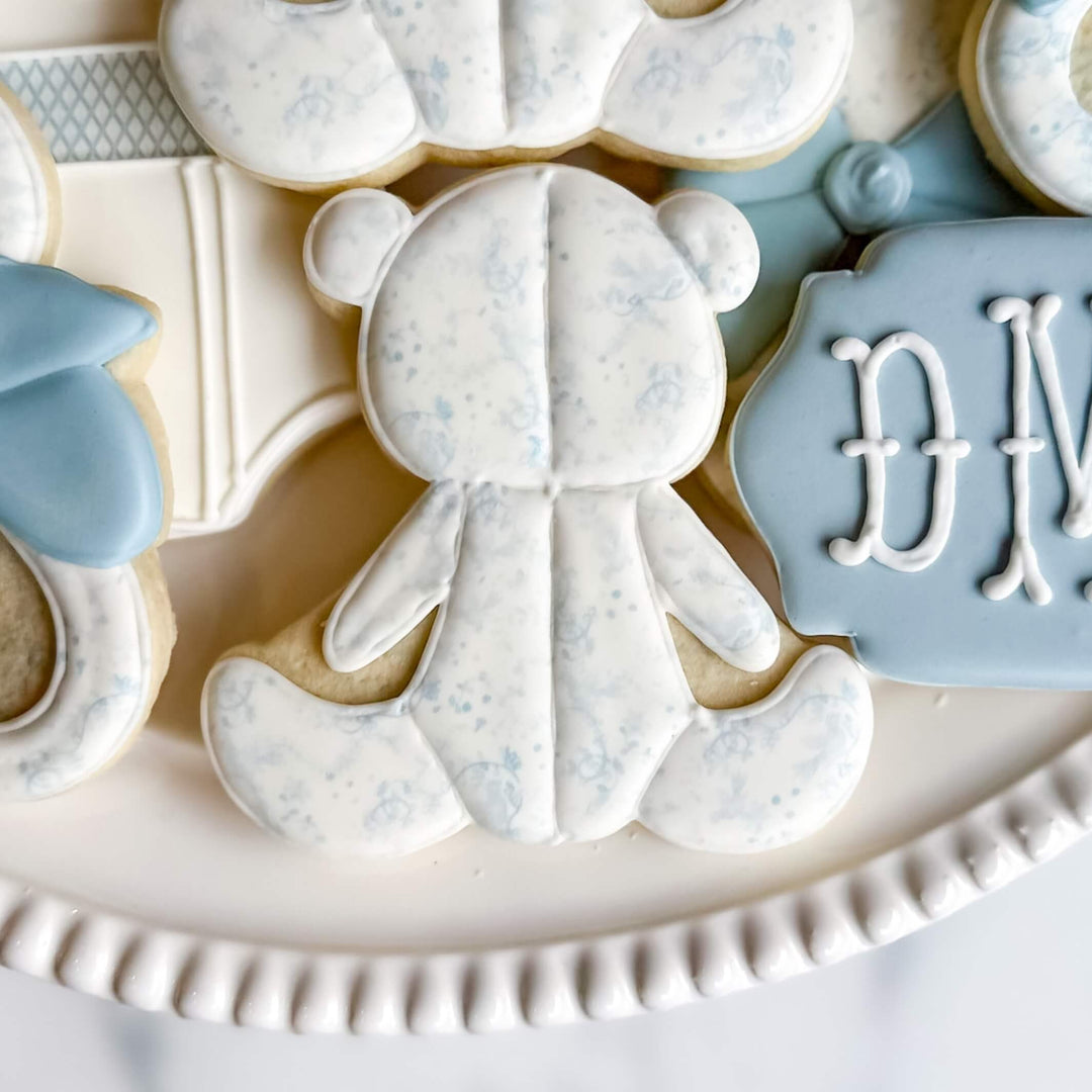 Adorable blue and white teddy bear sugar cookie from Baby Collection Perfectly You for boys' celebrations.