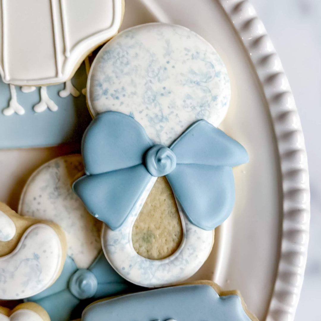 Adorable blue and white decorated rattle cookie perfect for baby boy celebrations.