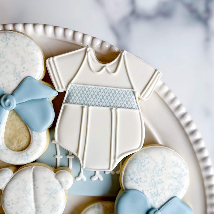 Adorable decorated onesie cookie for a baby boy celebration, part of a charming cookie collection.