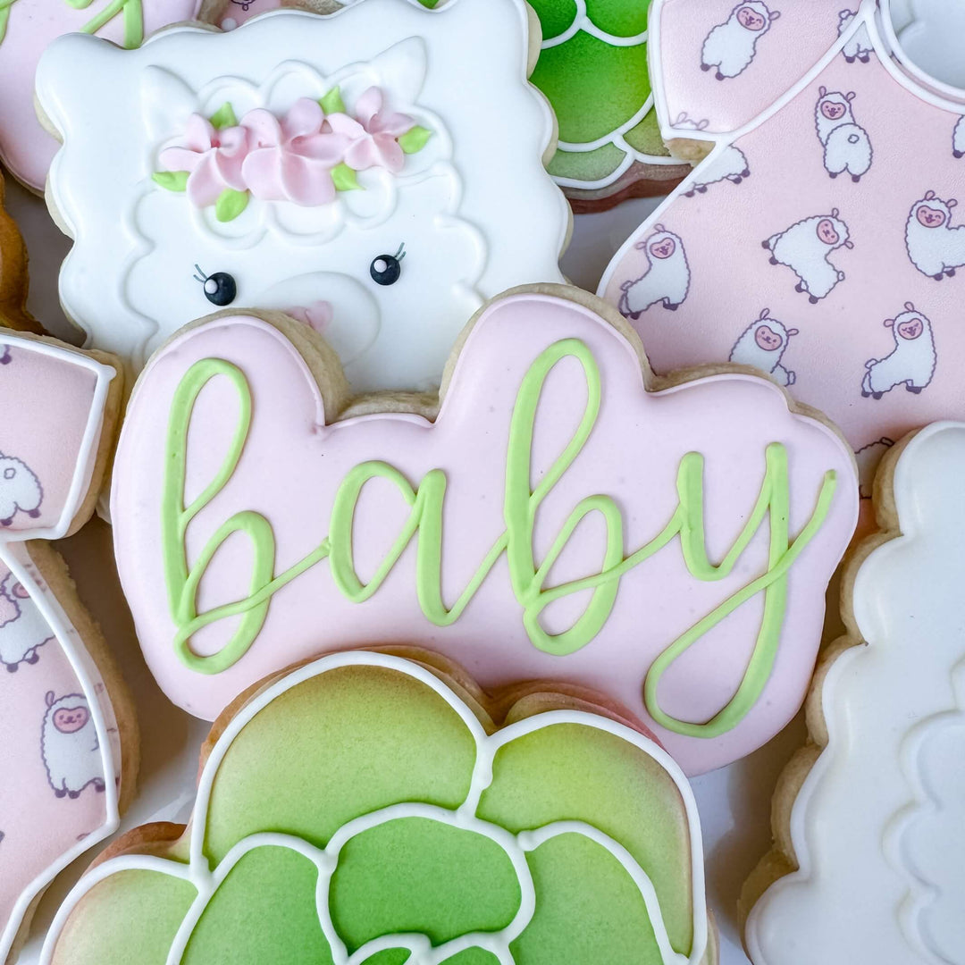 Decorated sugar cookies featuring a llama, floral designs, and 'baby' text for baby shower celebrations.