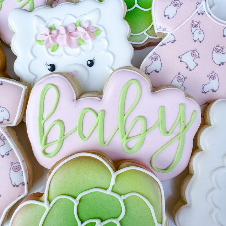 Decorated sugar cookies featuring a llama, floral designs, and 'baby' text for baby shower celebrations.