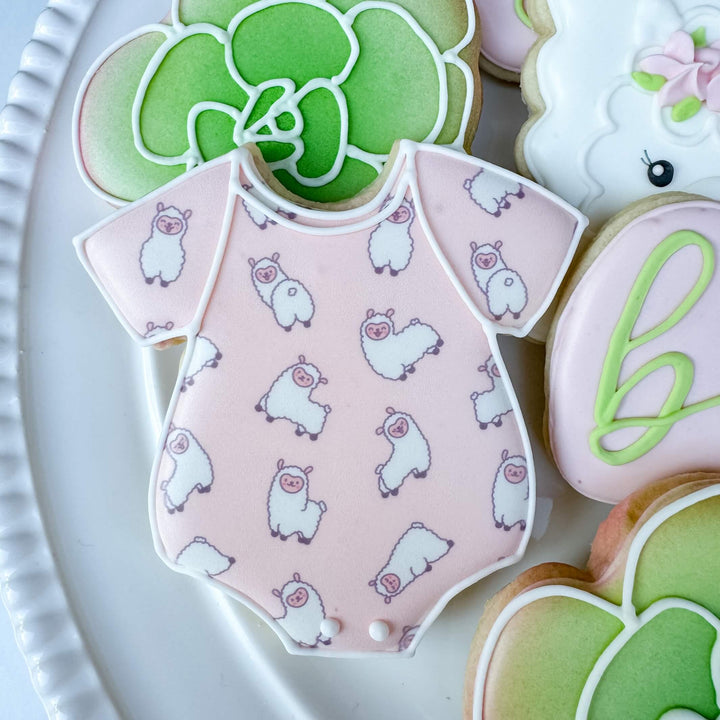 Cute llama onesie-shaped cookie decorated in pink with adorable llama patterns for baby showers.
