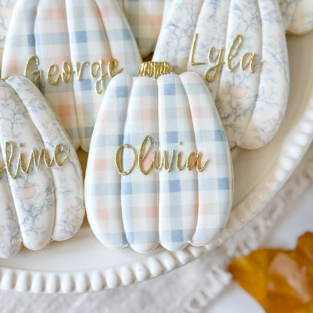 Thanksgiving pumpkin place card cookies from Southern Sugar Bakery decorated as festive holiday treats and table decor.